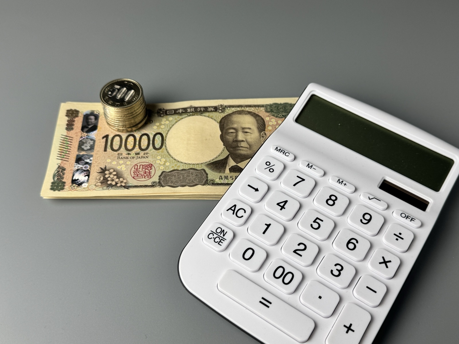 1万円札と電卓。実際に課金して1分単価を計算したときの実物
